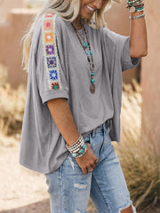 Grey t-shirt with colorful crochet detail on the sleeves and a loose fit.