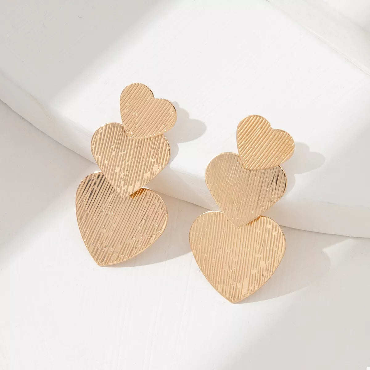 Gold heart-shaped dangle earrings with textured finish