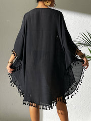 Black kaftan dress with crochet yoke and tassel trim, short sleeves, and flowy hem.