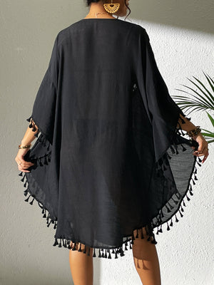 Black kaftan dress with crochet yoke and tassel trim, short sleeves, and flowy hem.