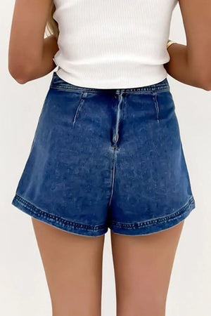 Denim wrap skort in medium wash with patch pockets and asymmetrical hem.