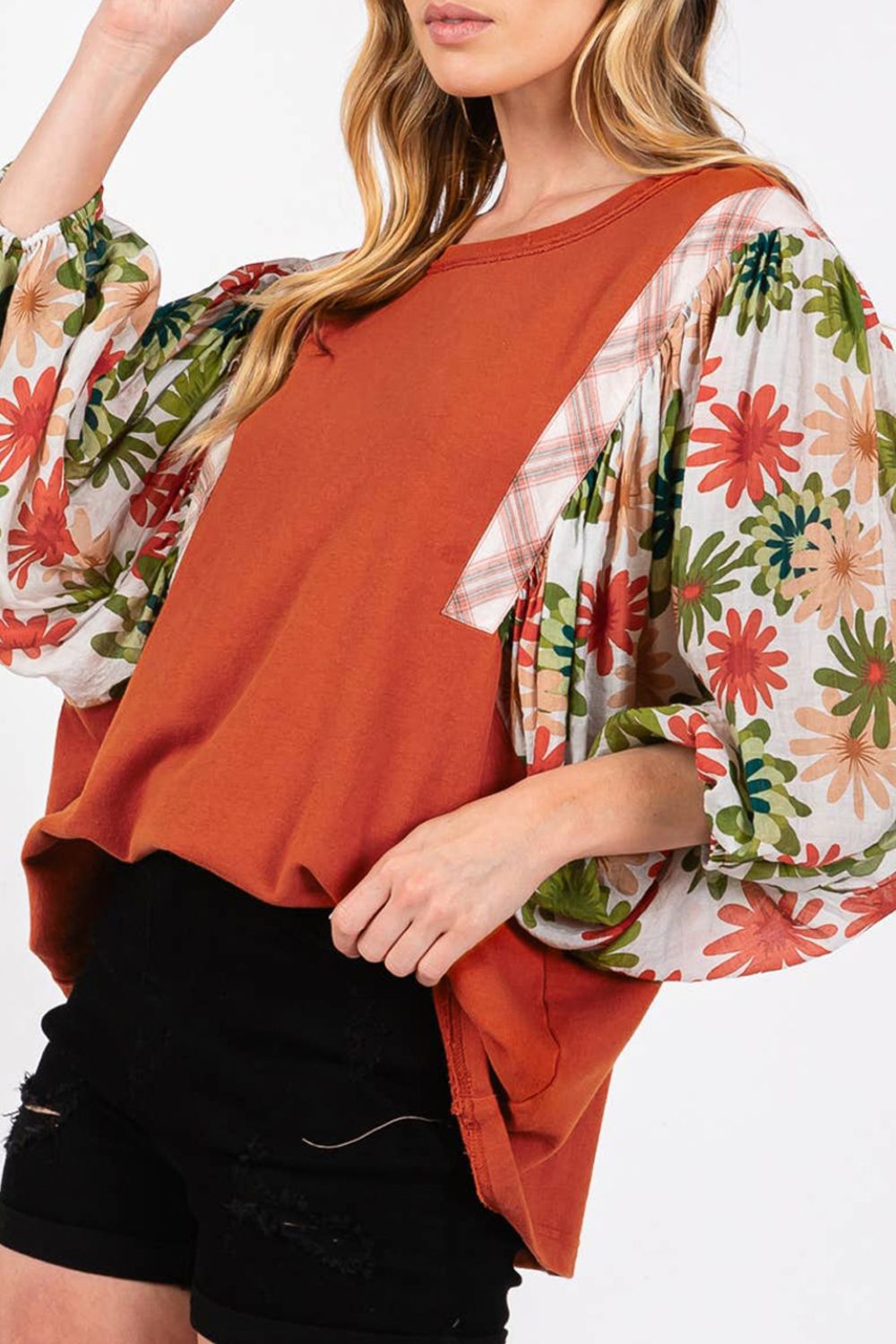 Orange-red blouse with floral patchwork balloon sleeves and plaid accents.