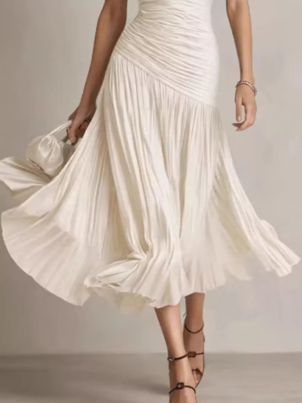 Beige ruched midi dress with a flowing pleated skirt and a-line cut.