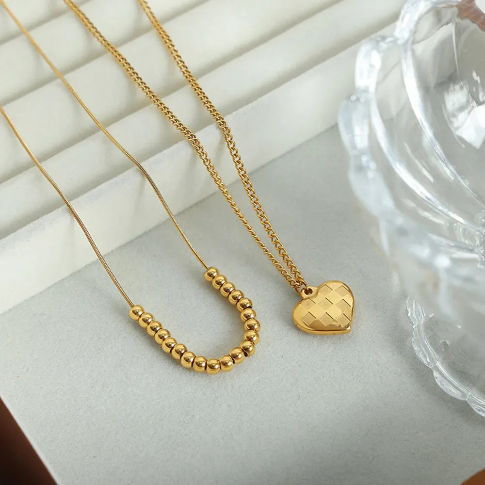 Gold layered necklaces with beaded chain and checkered heart charm