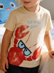 Beige cotton toddler tee with a playful lobster graphic and "Fun on the shore!" text.
