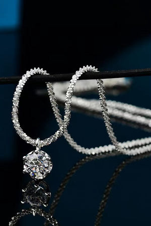 Silver pendant necklace with a textured chain and a round moissanite stone.