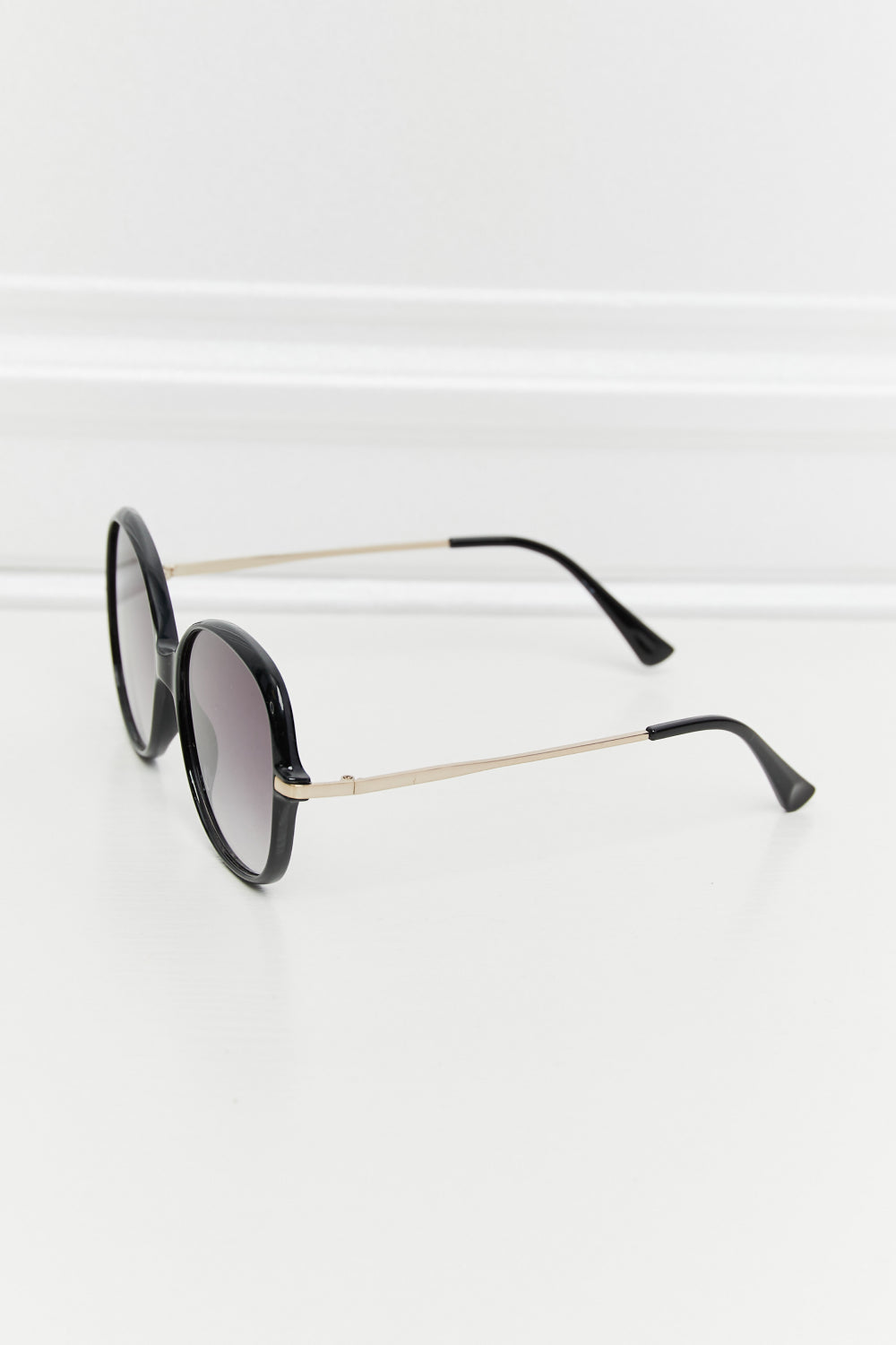 Oversized black round frame sunglasses with gold temples and gradient lenses.