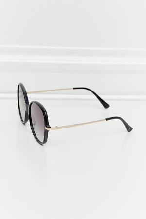 Oversized black round frame sunglasses with gold temples and gradient lenses.