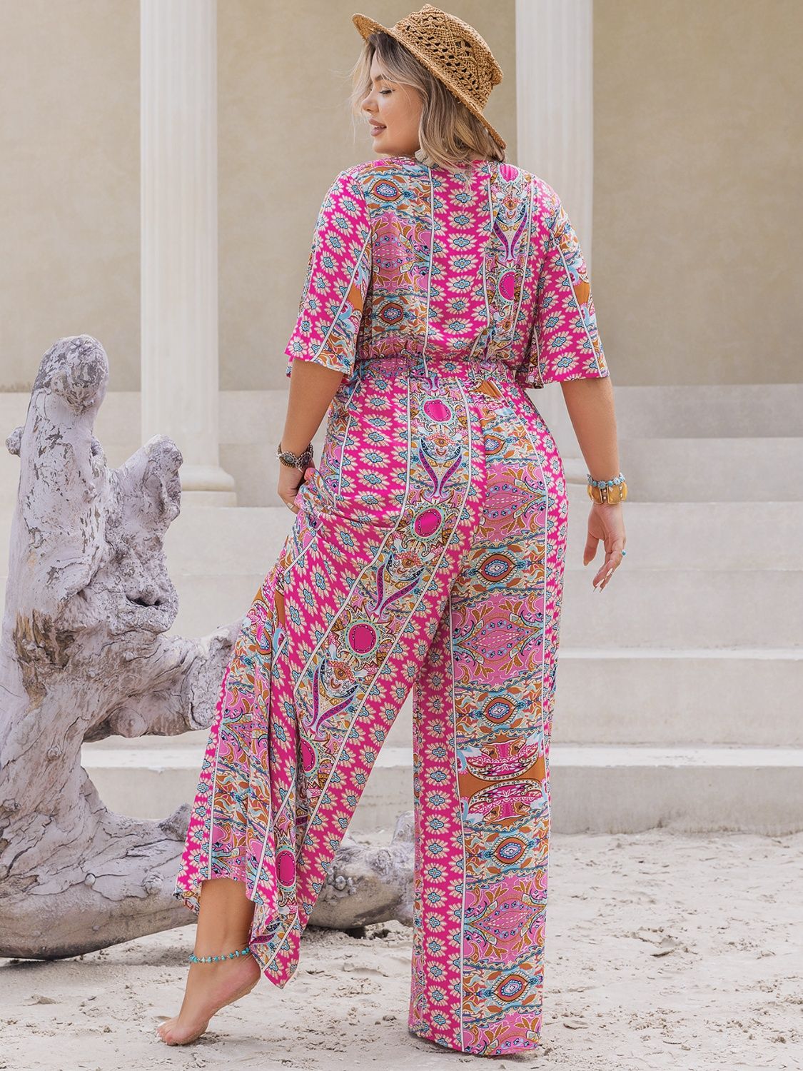 Bohemian palazzo jumpsuit in Deep Rose with bell sleeves and a vibrant paisley print.