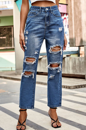 Distressed straight leg denim jeans in medium wash with ripped detailing.