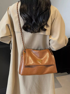 Brown shoulder bag with flap and chain detail, gold triangle accent