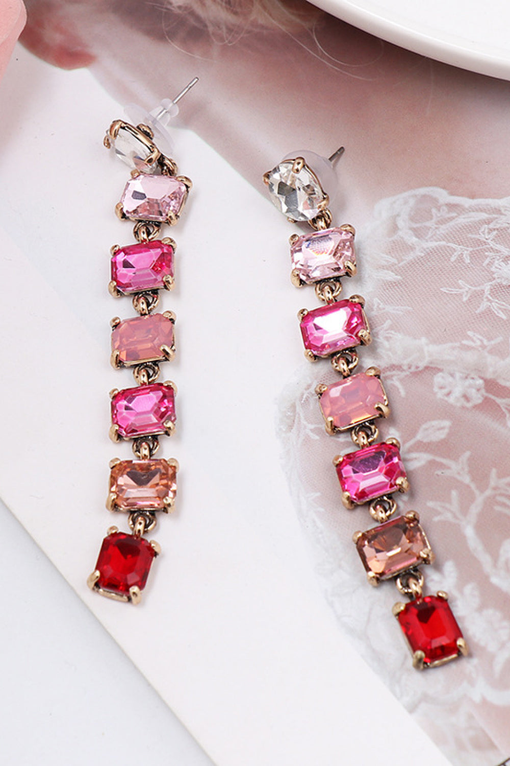 Ombre gemstone cascade earrings with pink, red, and clear stones on gold alloy.
