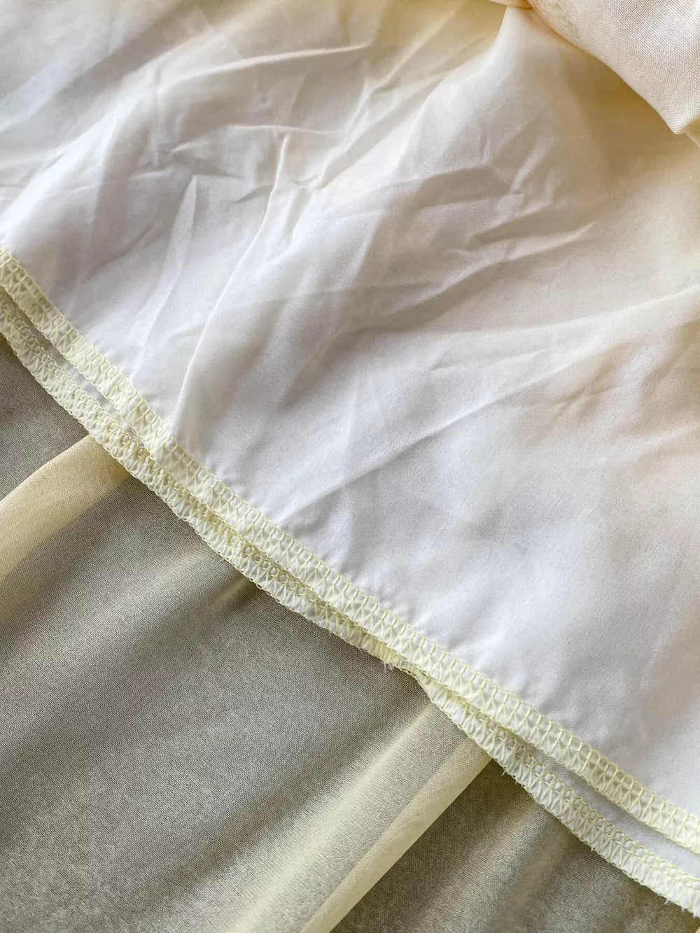 Floral ruffled two-piece ensemble detail showing sheer yellow fabric layered under white with decorative stitching.