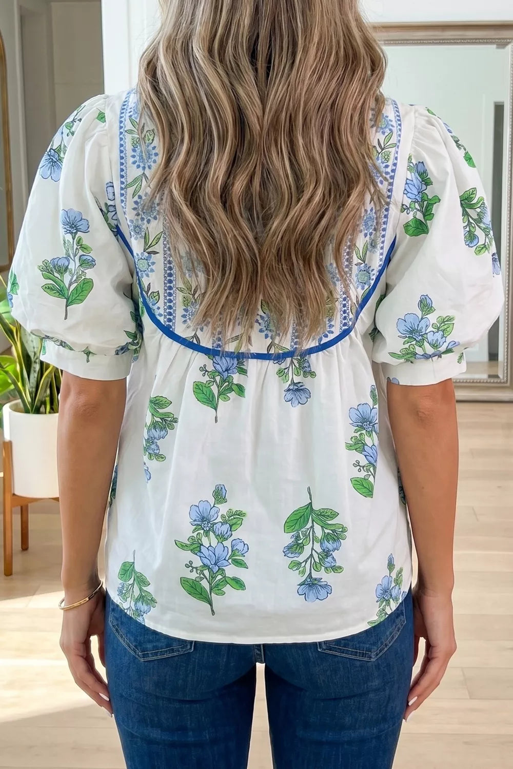 White polyester shirt with blue floral print, puff sleeves, and embroidered neckline detail.