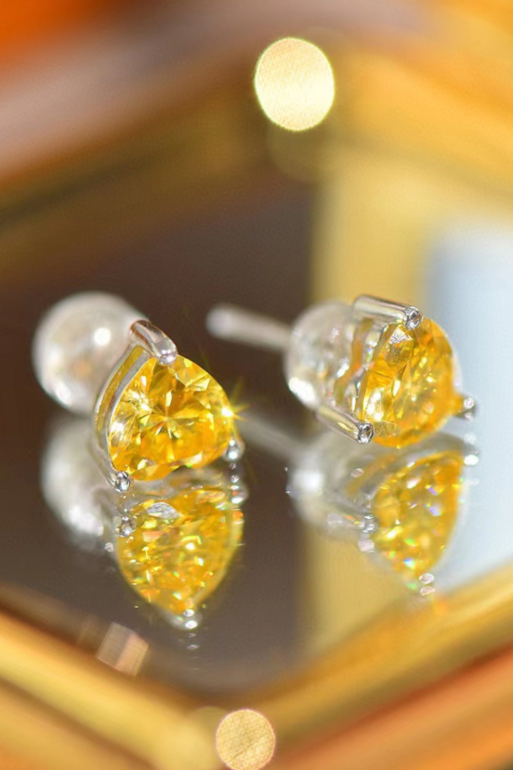 Yellow heart moissanite stud earrings with silver settings.