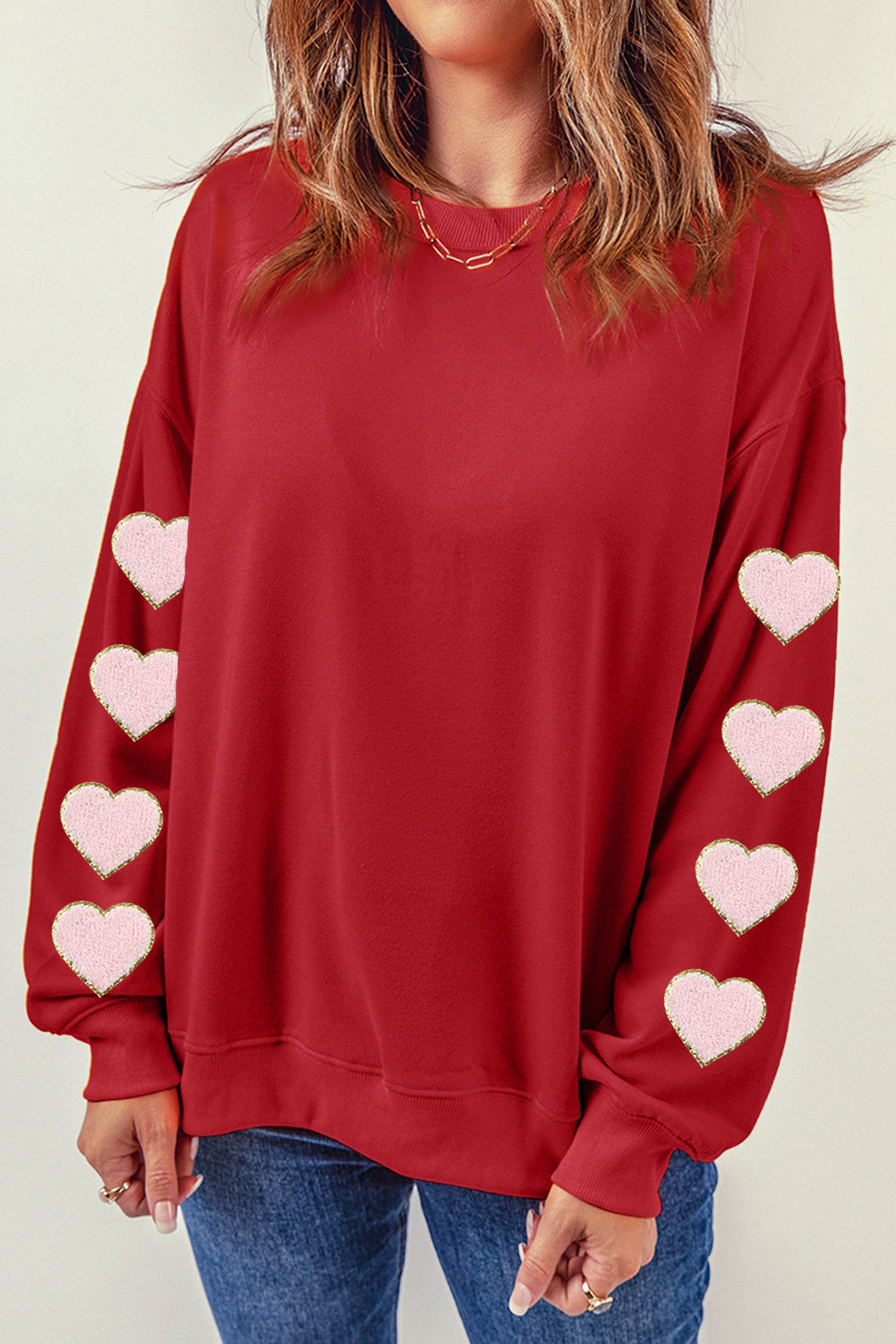 Deep red sweatshirt with pink heart appliqué details on the sleeves.