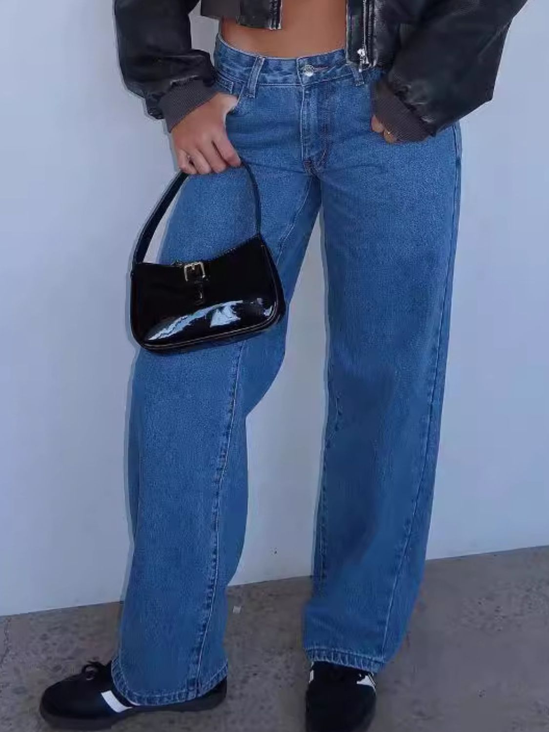 Blue wide-leg denim jeans with contrast stitching and a black patent handbag.