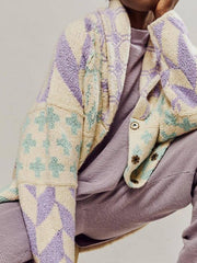 Geometric patchwork knit cardigan in cream with purple and teal patterns, featuring snap closures.