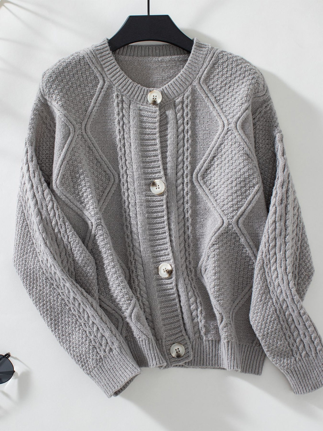 Gray cable-knit button-down cardigan with diamond and braid textures.