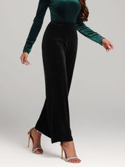 Black velvet palazzo trousers with a wide leg and high waist, styled with heels.