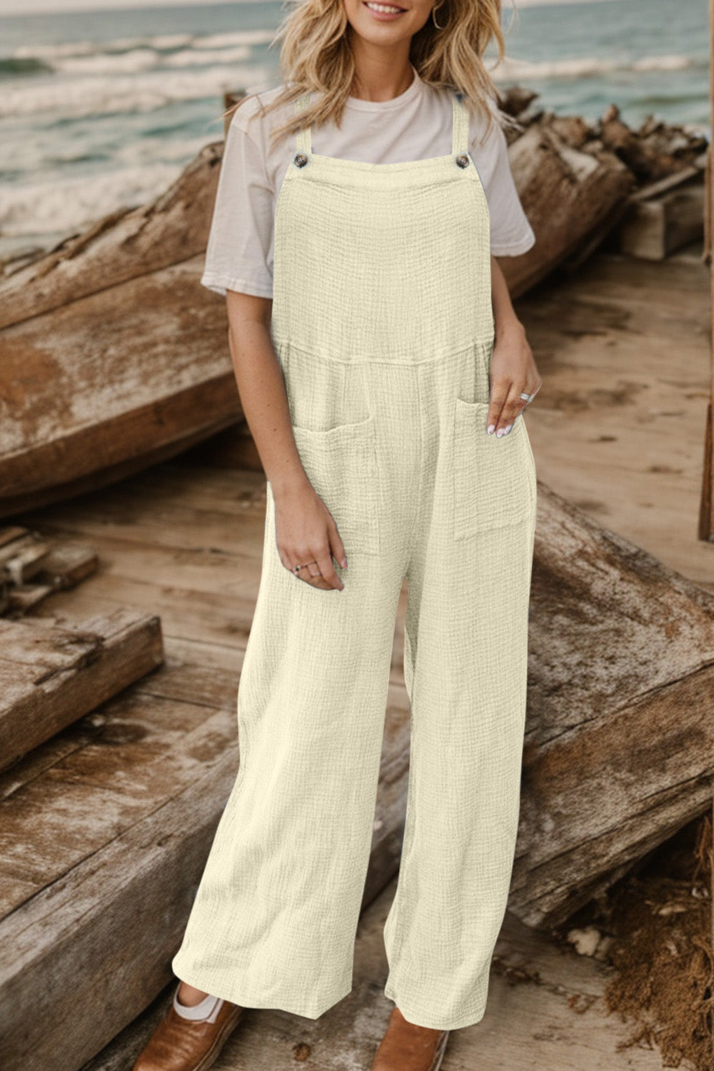 Cream textured cotton overalls with square pockets and wide legs.