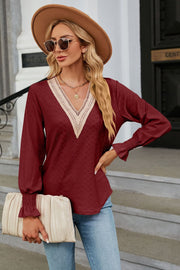 Burgundy textured V-neck blouse with lace trim and smocked cuffs.