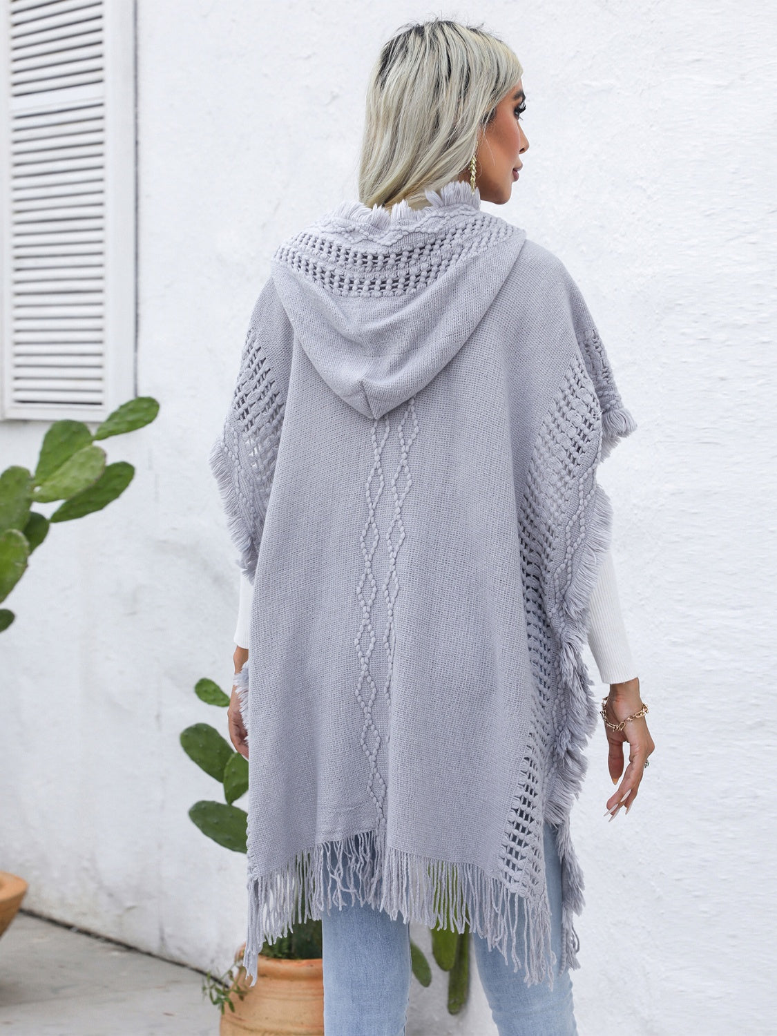 Gray knit poncho with fringe, crochet detail, and diamond pattern.