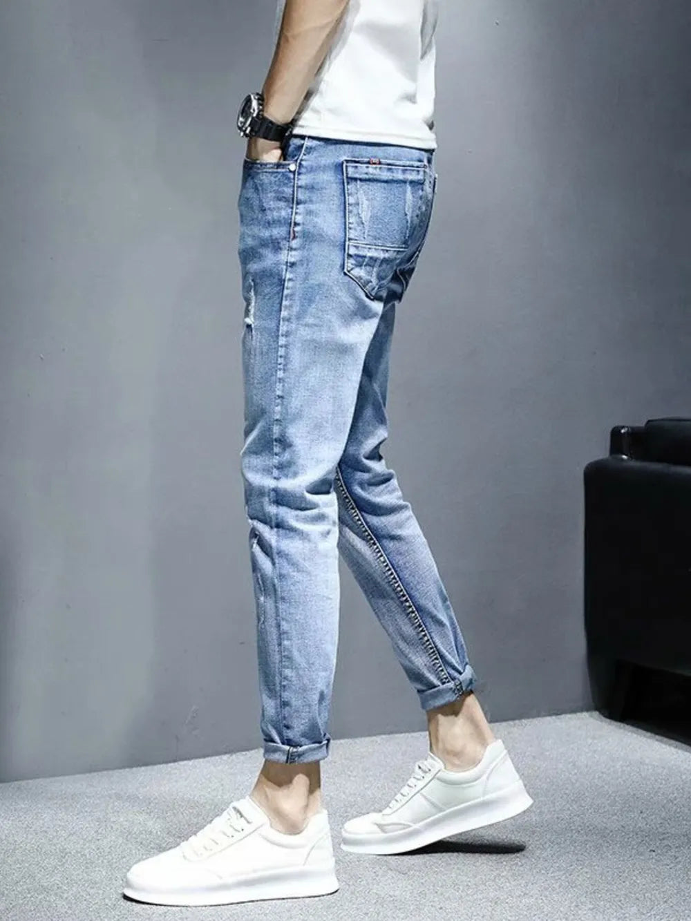 Light wash distressed slim fit jeans with rolled cuffs and whiskering detail.