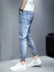 Light wash distressed slim fit jeans with rolled cuffs and whiskering detail.