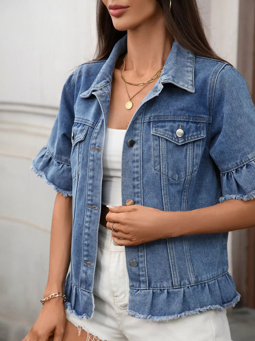 Blue denim trucker jacket with ruffled sleeves and hem, button-up front, and raw edges.