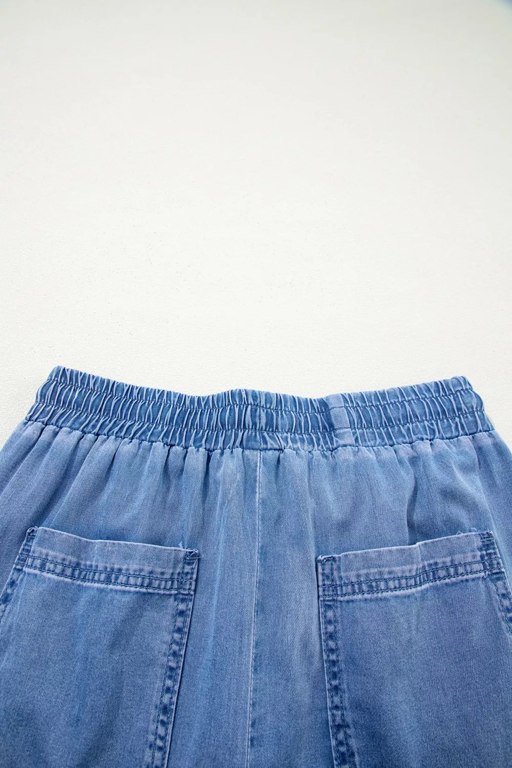 Maternity jeans in light blue denim with elastic drawstring waist and patch pockets.