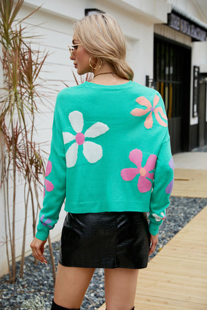 Teal acrylic sweater with drop shoulders and a colorful daisy motif pattern.