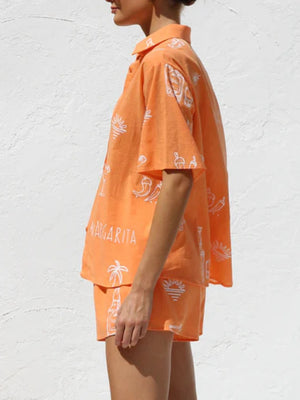 Tangerine resort set with white margarita and beach graphics, button-up shirt and shorts.
