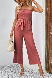 Smocked bodice wide-leg jumpsuit in watermelon pink with a tie belt and button detail.