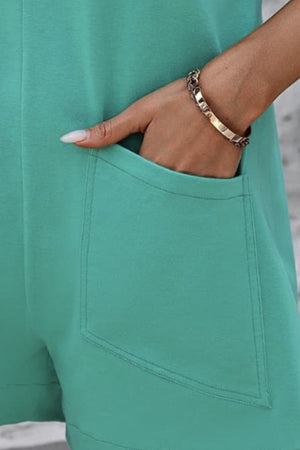 Turquoise romper with patch pockets, hand in pocket showing bracelet detail.