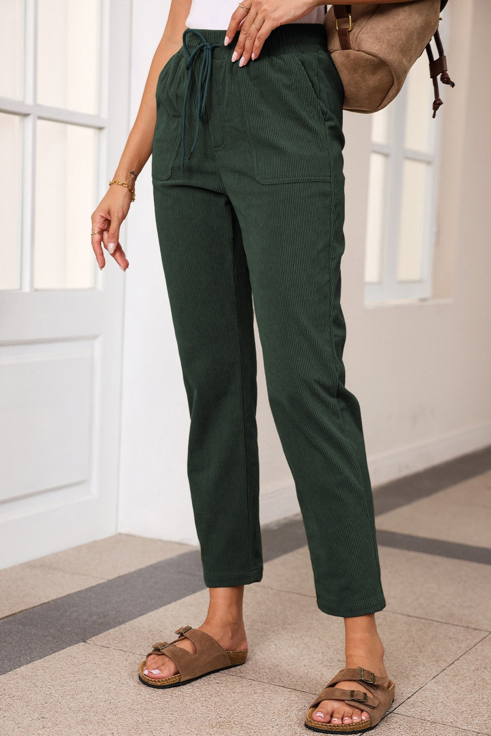 Dark green corduroy drawstring trousers with slant pockets and a relaxed fit.