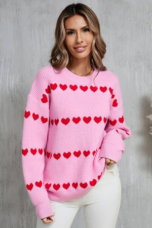 Pink knit pullover sweater with red heart stripe pattern and crew neck.