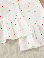 White cotton pajama set with red heart print and ruffled hem detail.