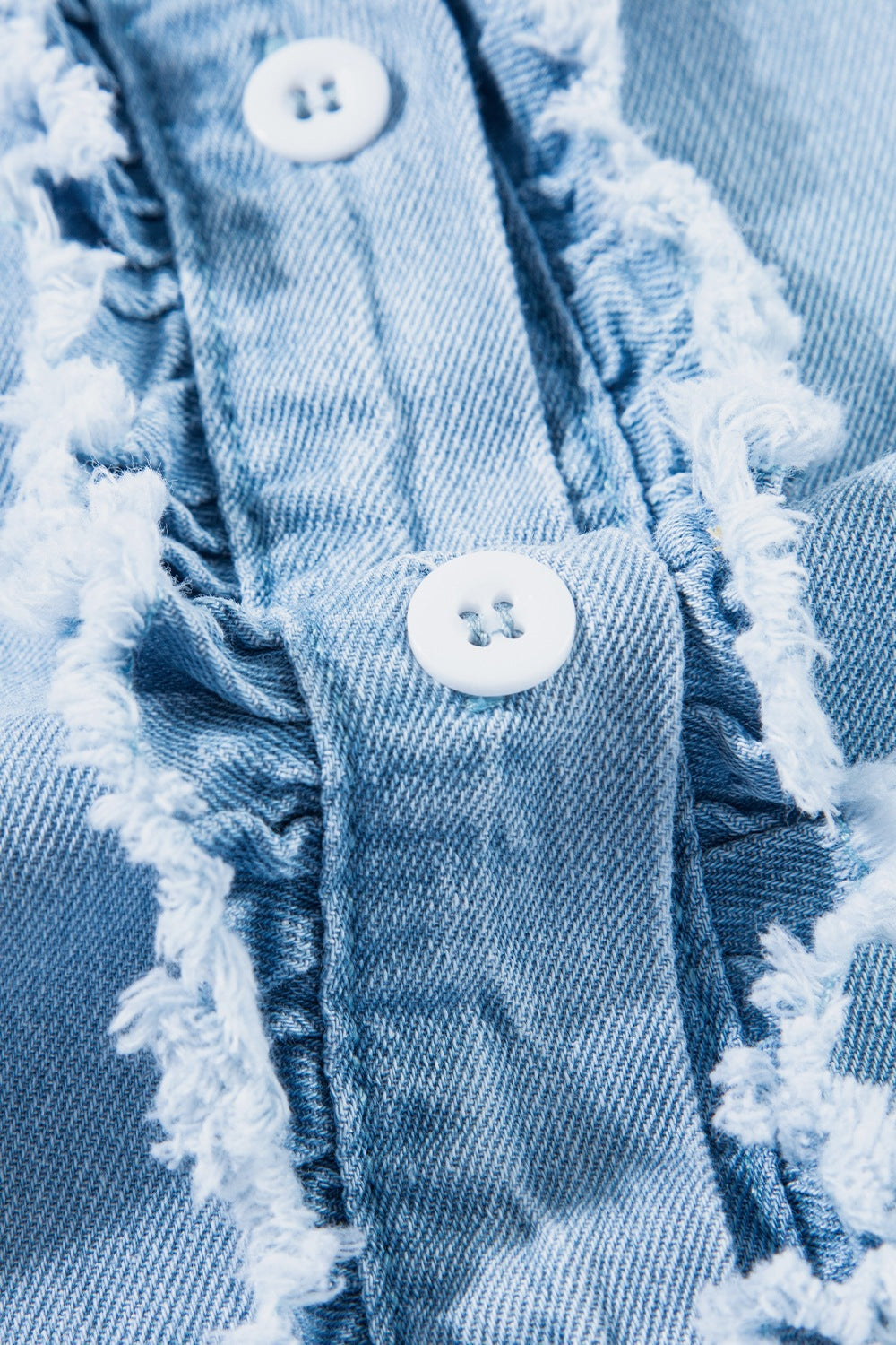 Light blue denim button-up shirt with frayed ruffle trim and white buttons.