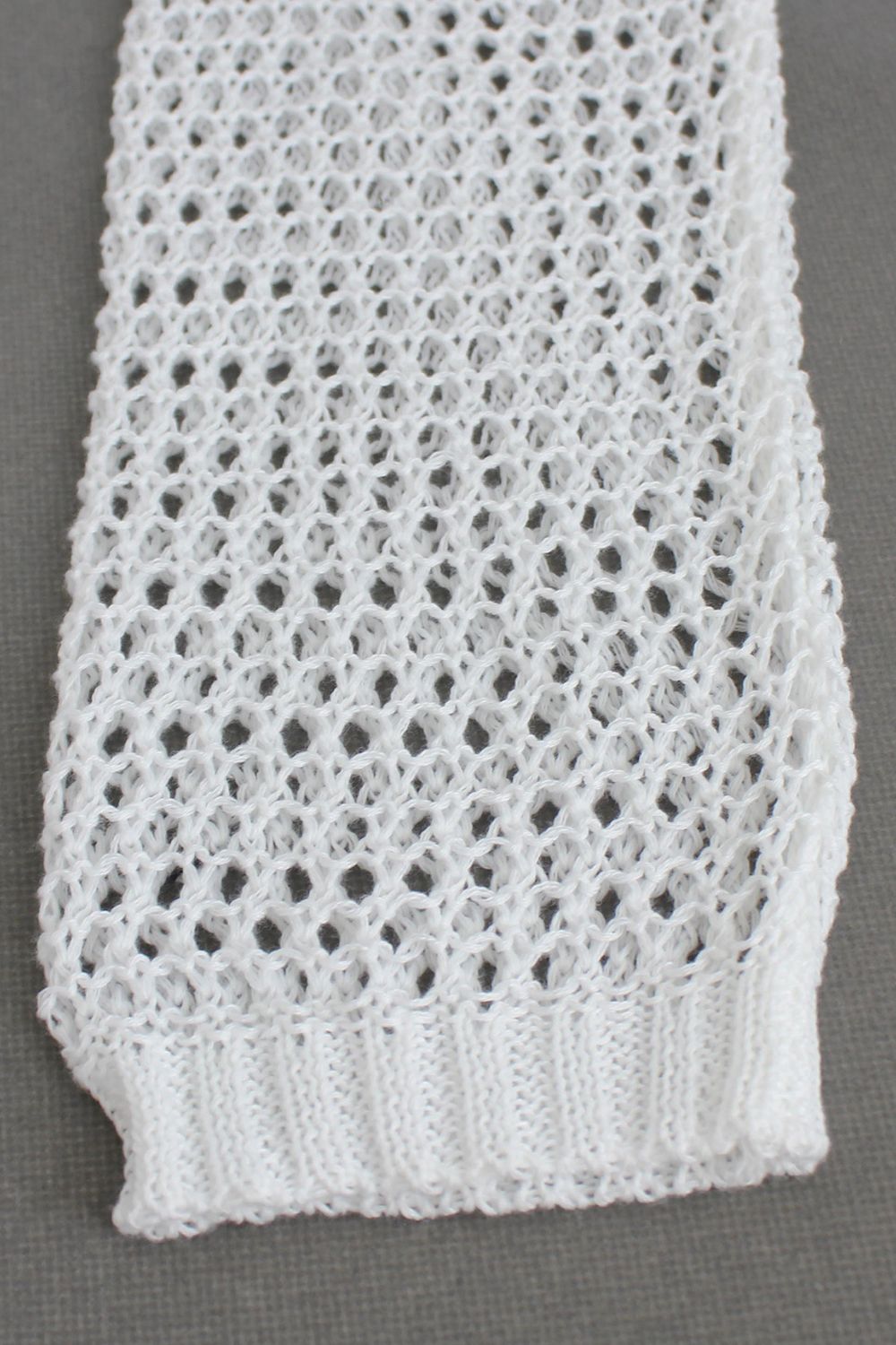 White crochet blouse with open knit pattern and ribbed hem detail.