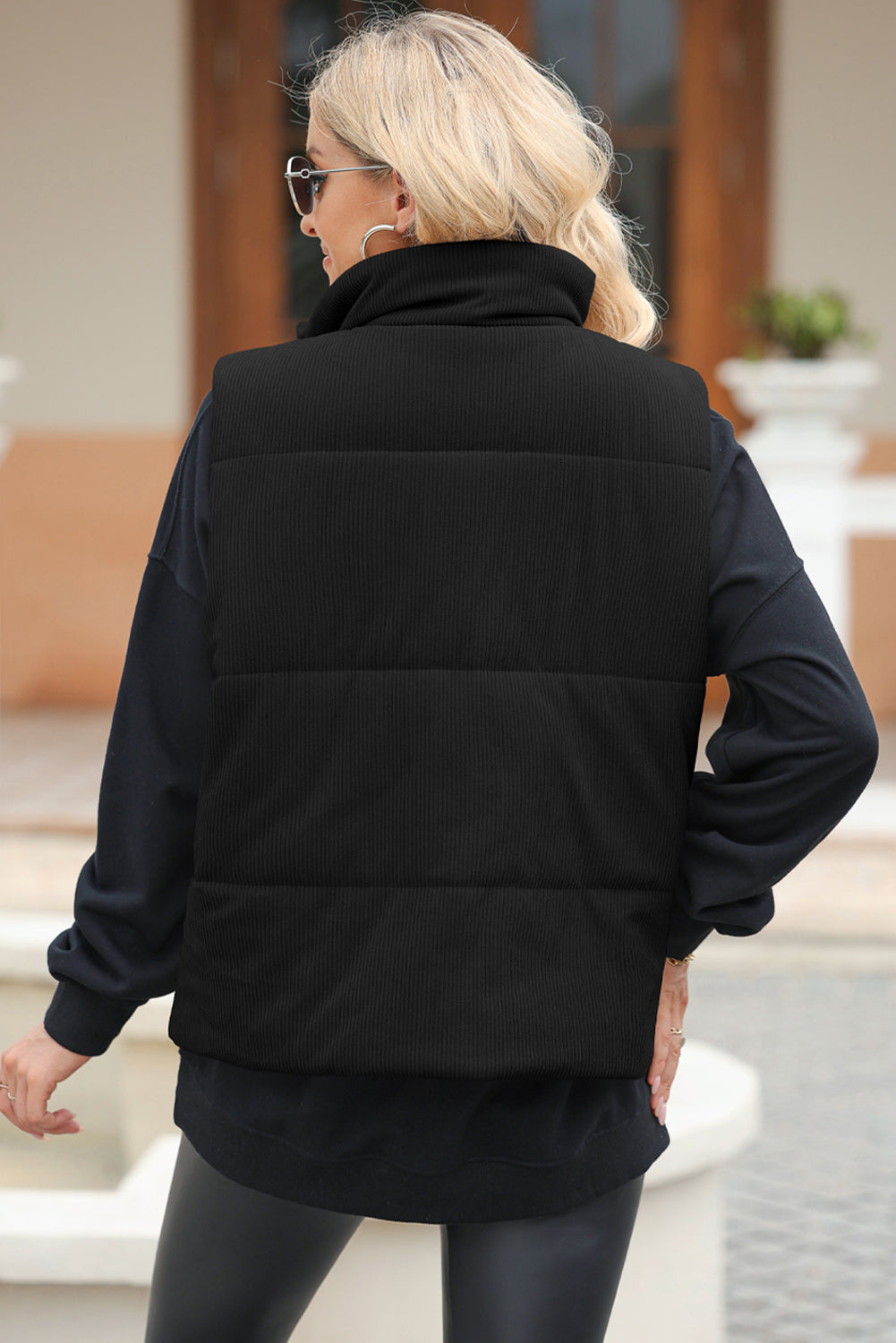 Black corduroy padded funnel neck vest with horizontal quilting.