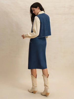 Peacock blue suede vest and skirt set with contrast stitching, worn over a cream sweater.