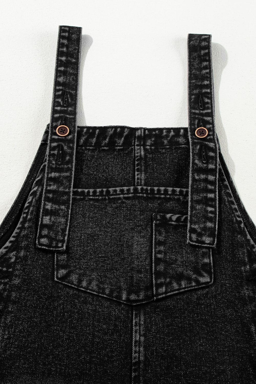 Black denim culotte overalls with distressed details and button straps.