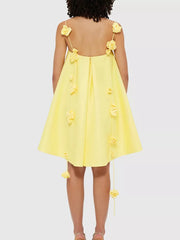 Yellow A-line mini dress with floral applique details on straps and hem.