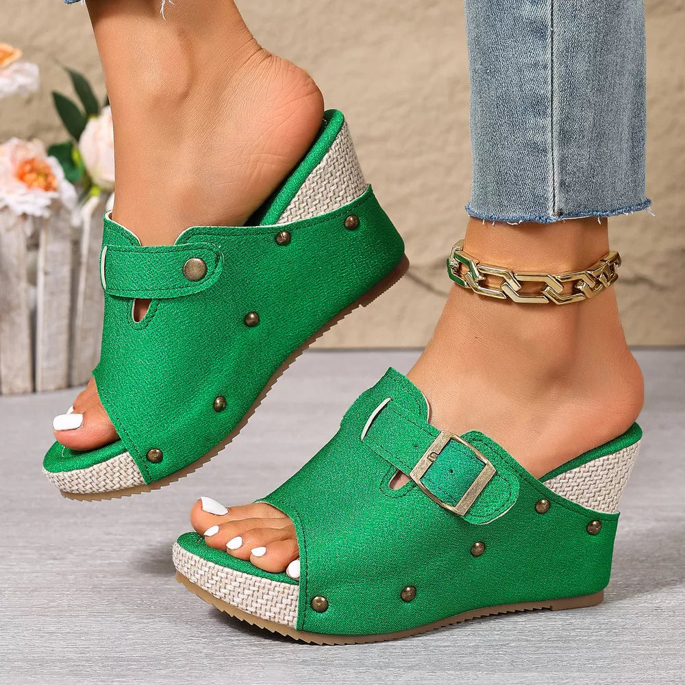 Green wedge sandals with decorative accents and buckle detail.
