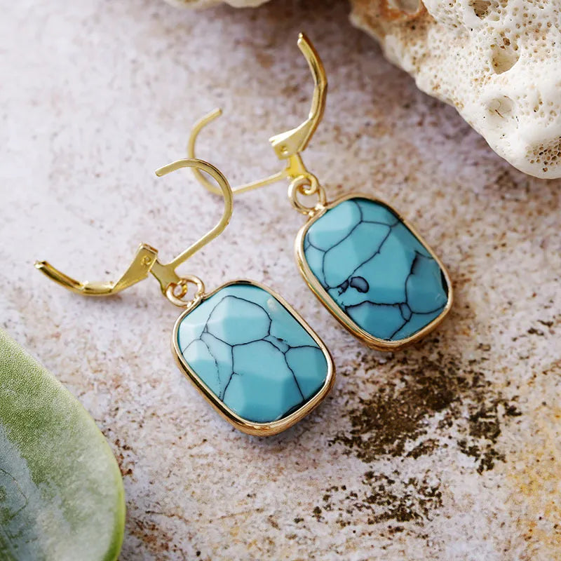 Turquoise stone and gold drop earrings with lever back closure.
