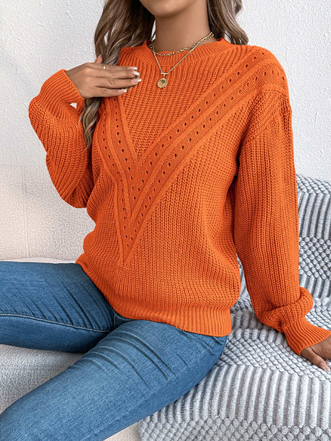 Orange acrylic sweater with chevron knit detail and eyelet accents.