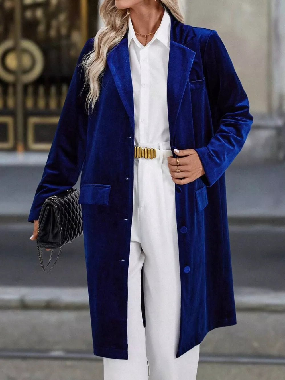 Elegant longline trench coat in dark blue velvet with lapel collar and buttoned front.