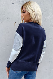 Geometric panel knit sweater in navy with gray and white sleeves, crew neck, and ribbed hem.