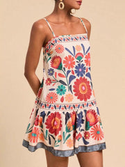 Playful printed mini dress with spaghetti straps and tiered skirt in multicolor floral pattern.